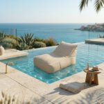 Eine beige, schwimmende Outdoor-Sonnenliege in Leinenoptik auf dem klaren Wasser eines modernen Infinity-Pools mit Blick auf das Meer bei sonnigem Wetter.